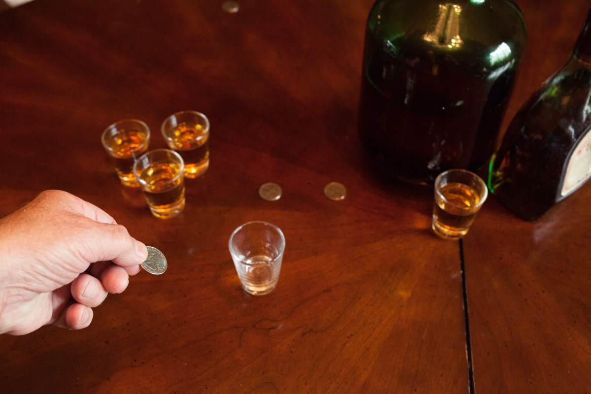One player tries to bounce a quarter off the table into a cup or shot glass.