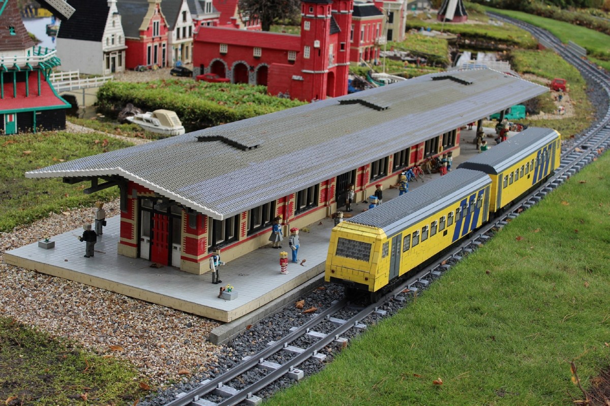 A train station with a train stopping to pick up passengers. 