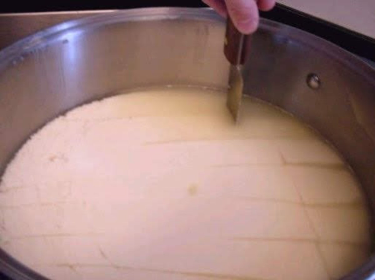 Using a long knife to cut the curds into a grid, so they can shrink.