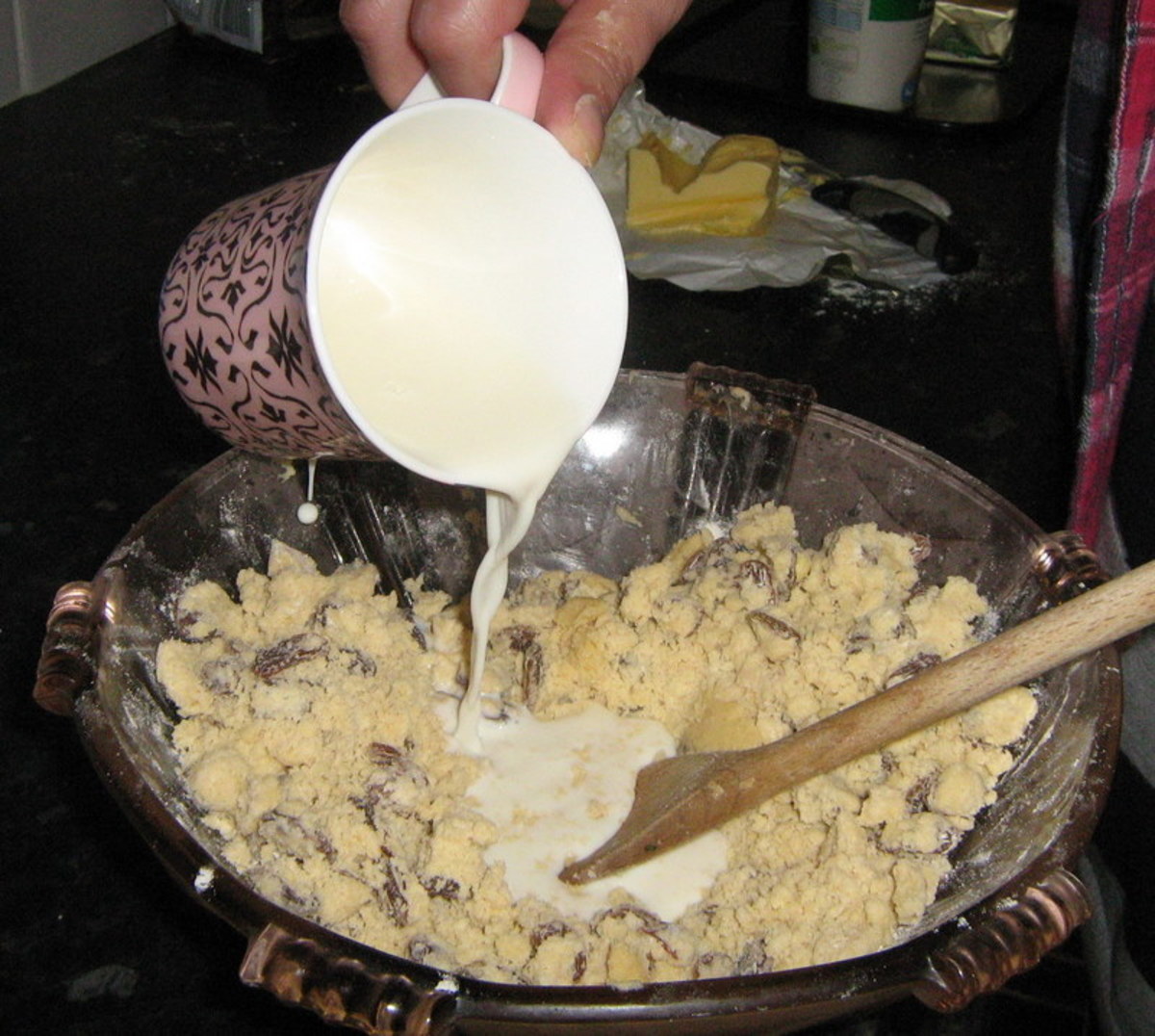 Make a hole in the centre of the mixture. Add the beaten egg and some milk into the bowl.