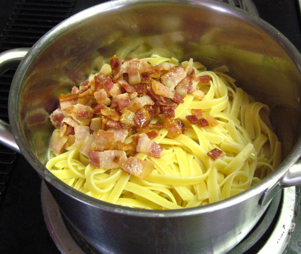 Drain the cooked pasta using a colander, and immediately pour the drained pasta back in the same hot pot it came from, keeping some cooking water. While stirring on medium heat, add the bacon with all its cooking juices and the egg mix. Stir.