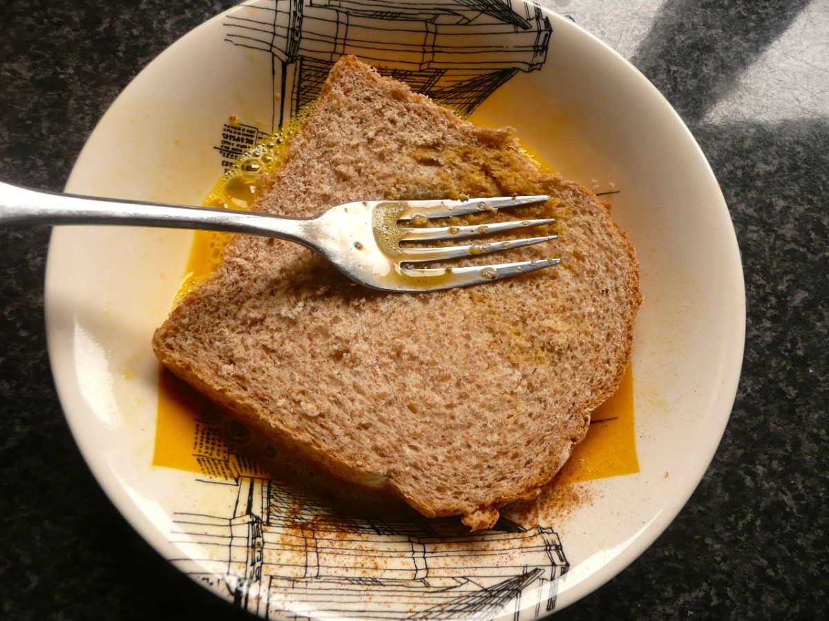 Place a slice of bread in the egg. Press lightly with a fork to speed up absorption of egg. 