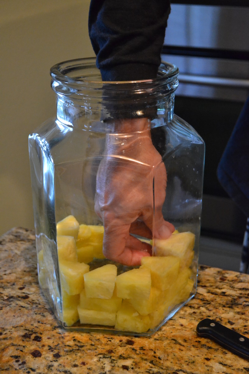 Step 1: Line the sides of a large glass jar with pineapple chunks.
