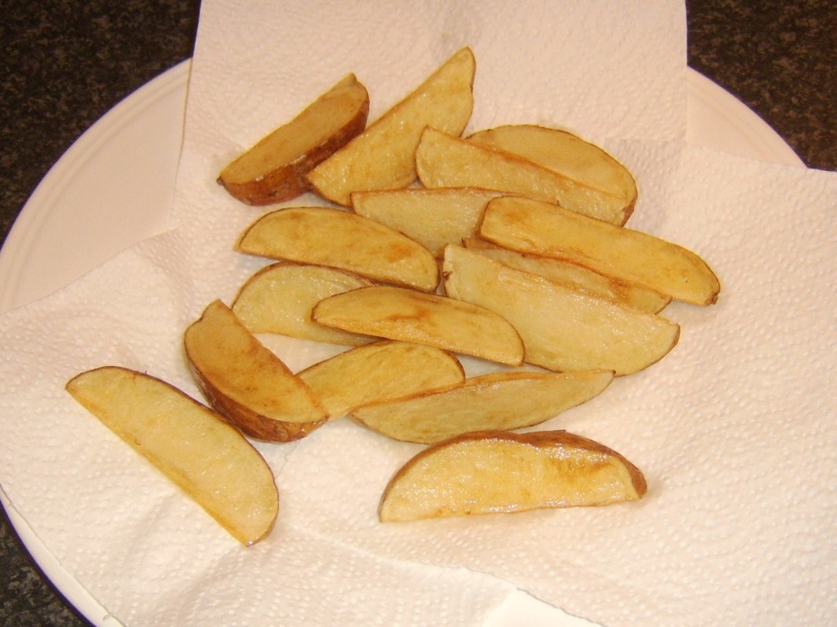 Deep fried potato wedges are drained on kitchen paper