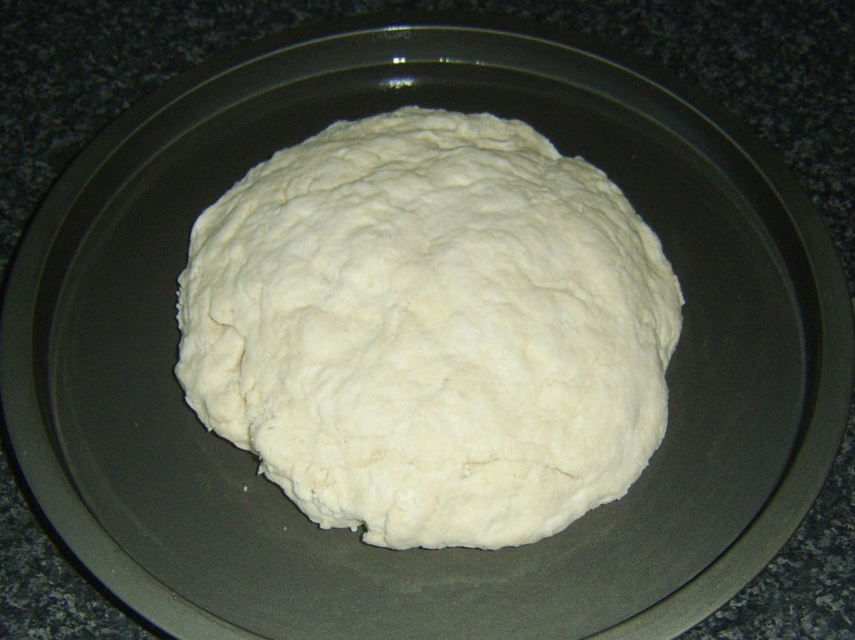 Soda bread dough ball is gently flattened in to a mound.