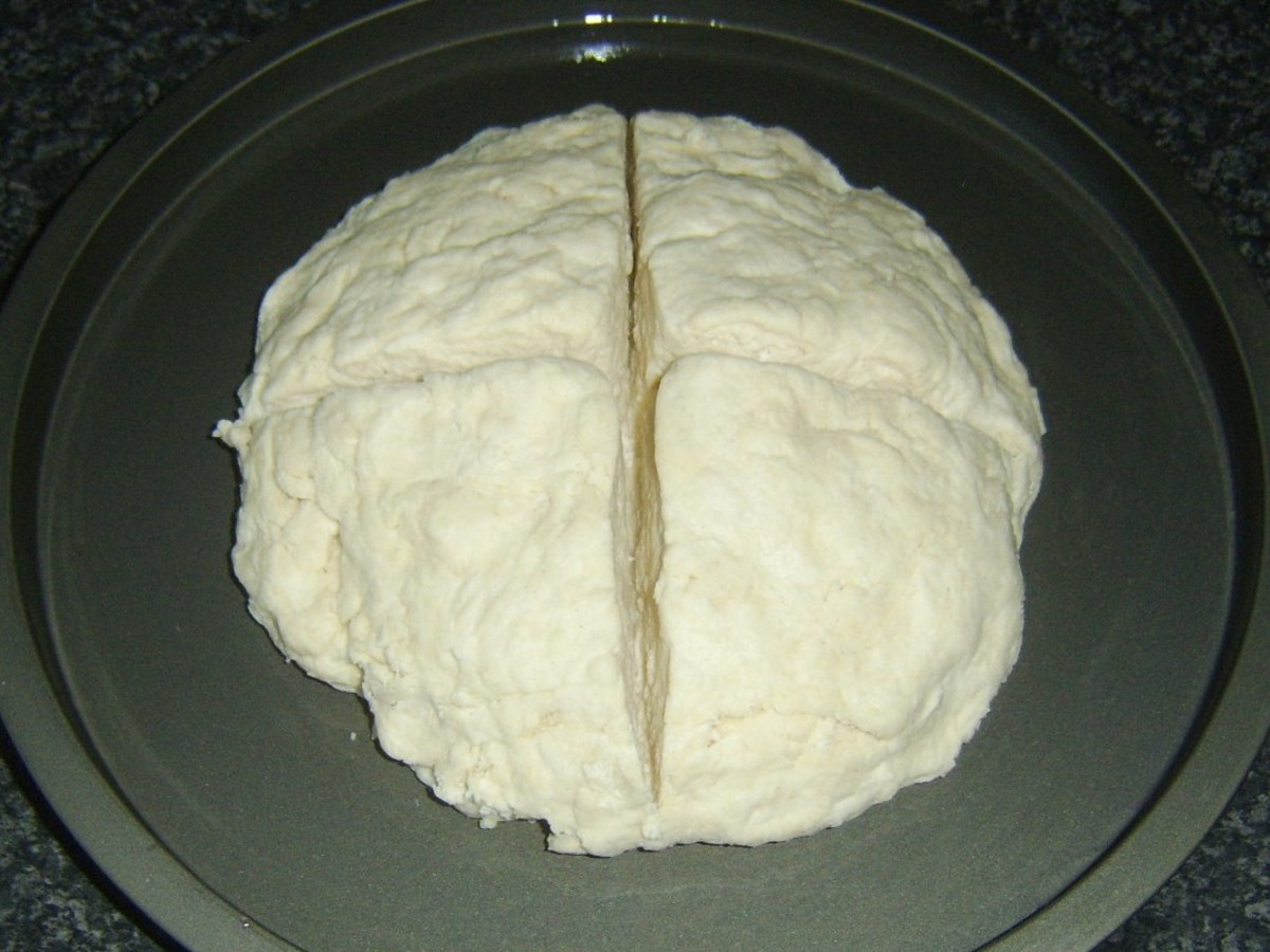 Soda bread dough is deeply cut for baking.