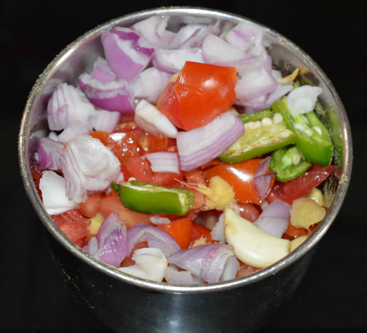 Step one: Grind chopped tomatoes, onions, garlic, ginger, and green chilies to make a paste.