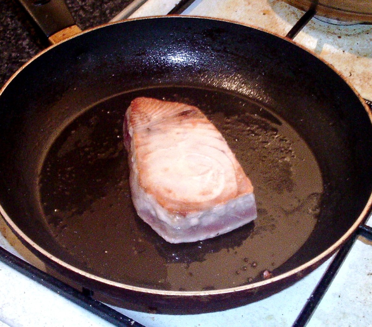 Tuna fillet is turned to fry on its second side.