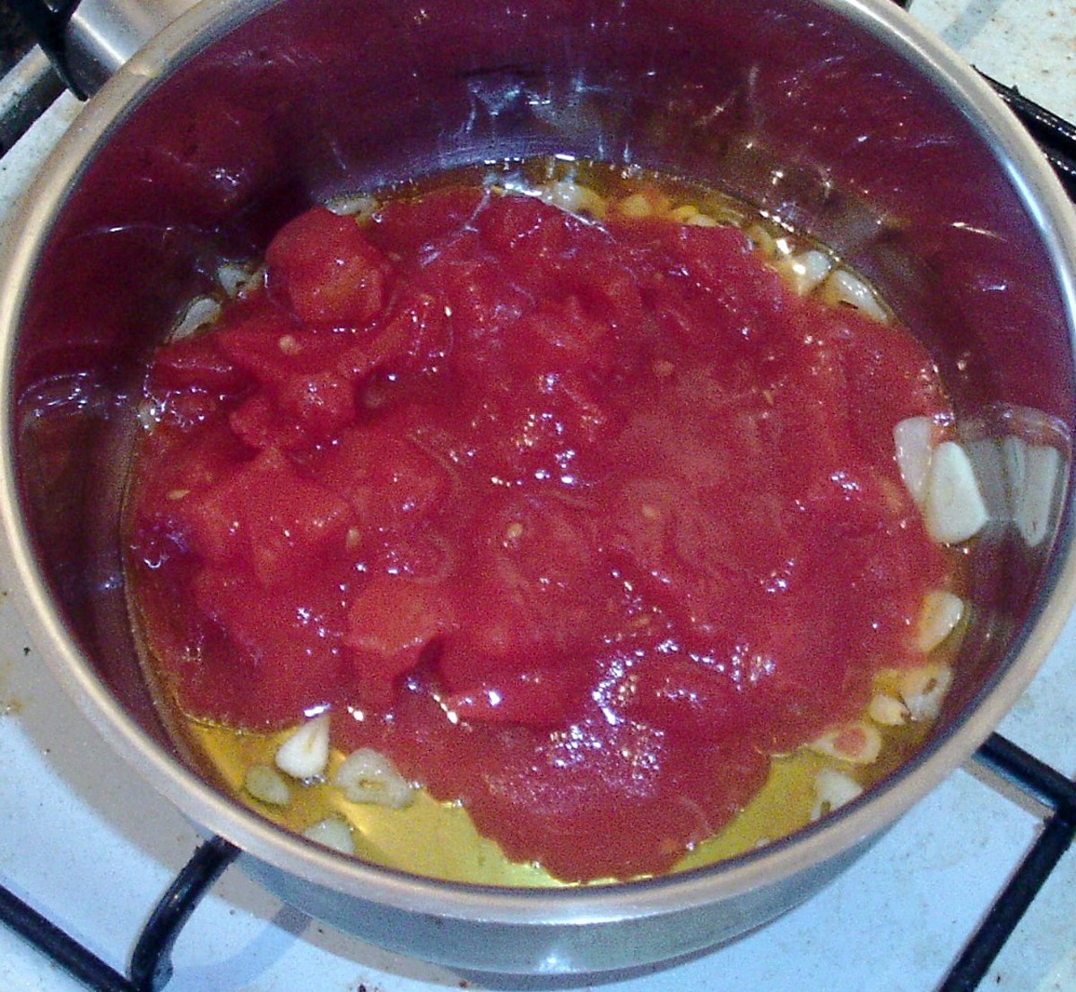Canned tomatoes are added to softened garlic.