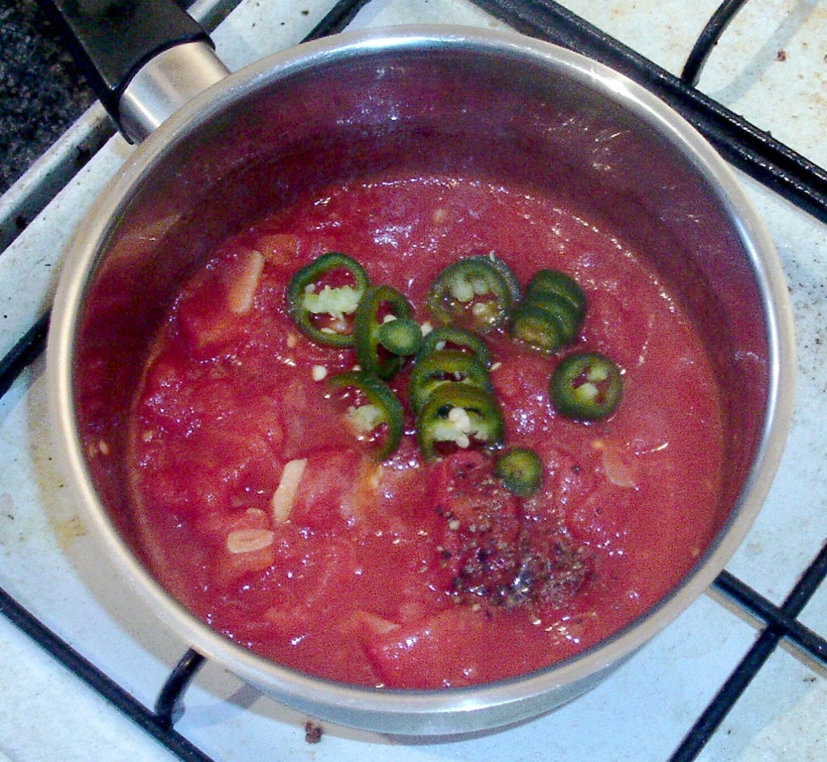 Sliced chilli and seasonings are added to saucepan.
