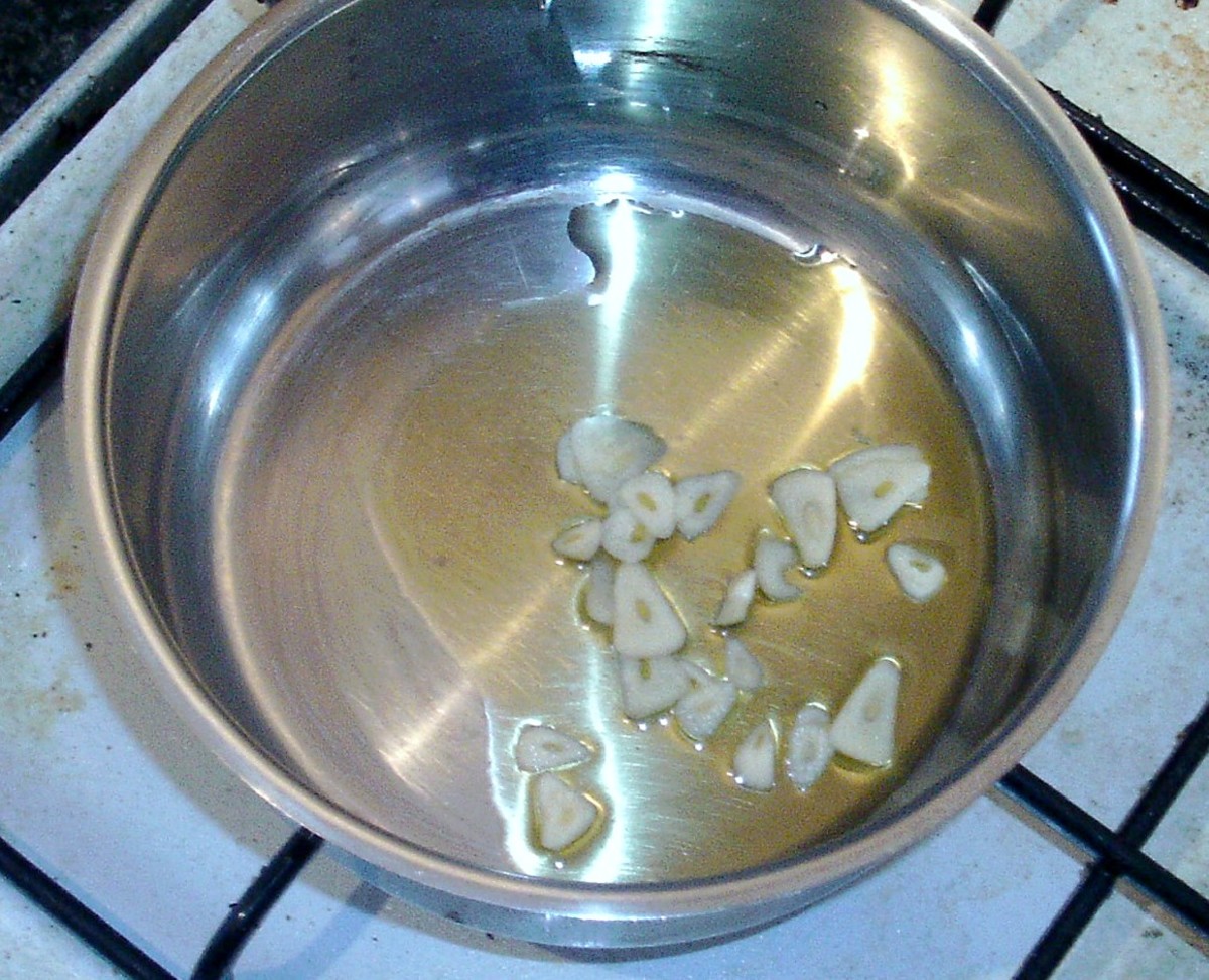 Sliced garlic is added to heated olive oil.