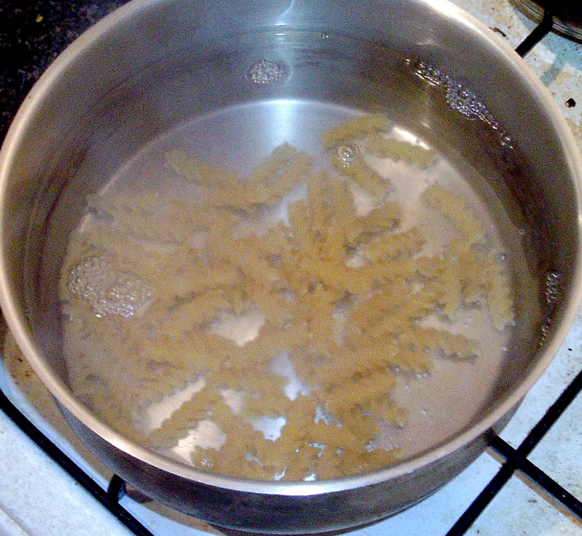 Fusilli pasta is added to boiling salted water.