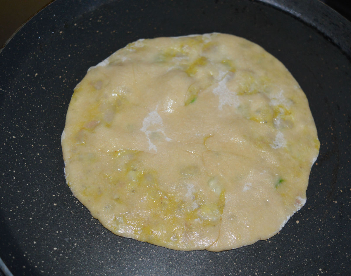Step six: Heat a griddle. Grease it with ghee or oil. Place the disc on it. Add a few drops of ghee or oil on the top. Flip it, once the bottom side becomes golden brown. Roast both the sides, till you see golden brown spots on the disc.