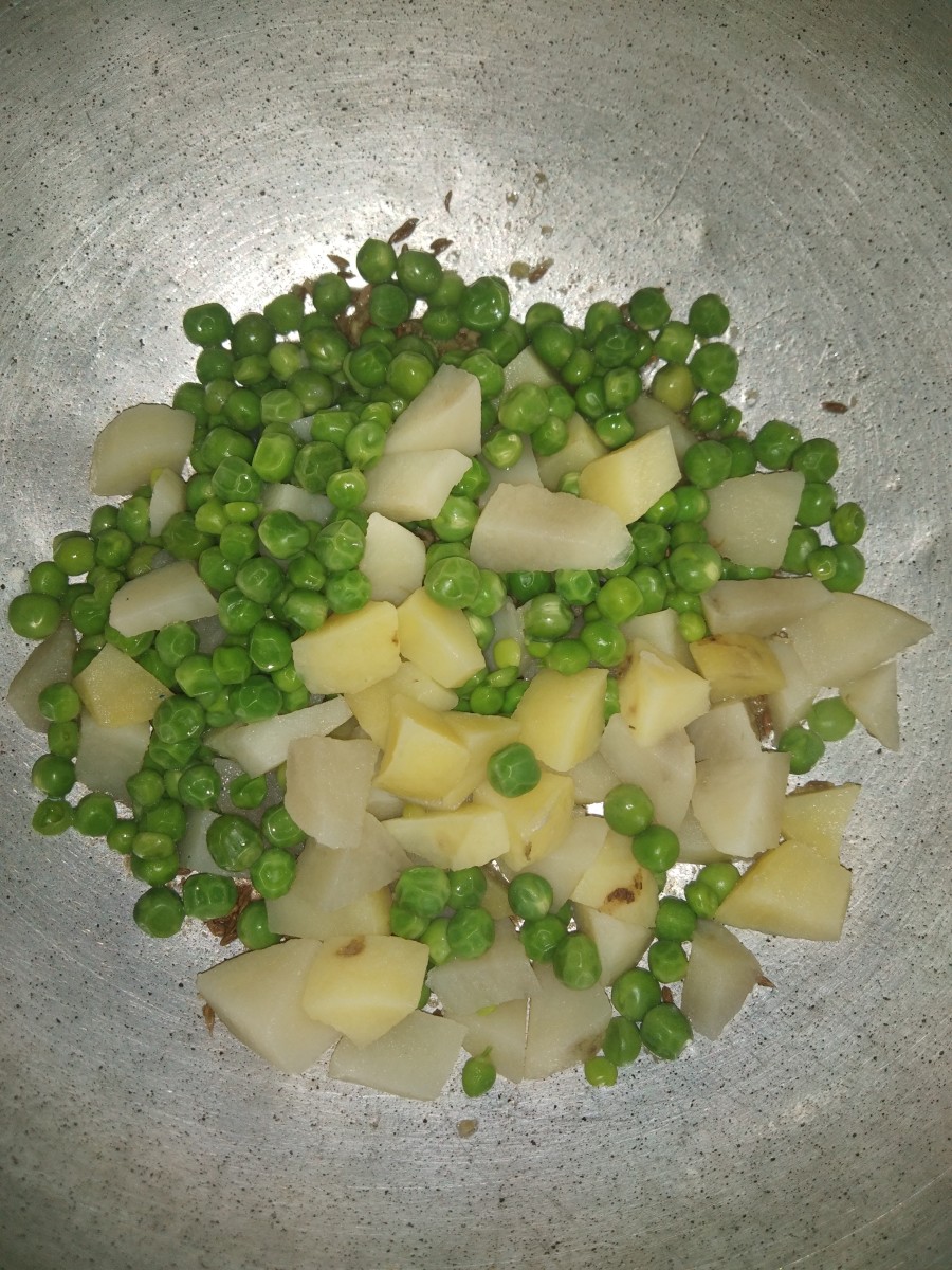 Add cooked peas and remaining  potato cubes to the seasoning.