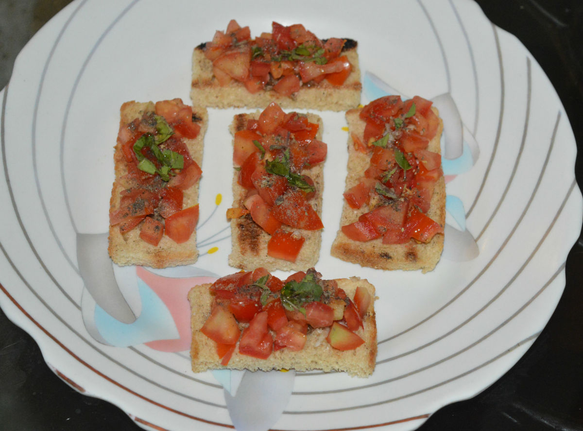 Step three: Place the bread slices on a plate. Generously spread chopped tomatoes. Sprinkle salt, Italian dry mixed herbs, basil, and pepper powder. Add a few drops of extra virgin olive oil on top.