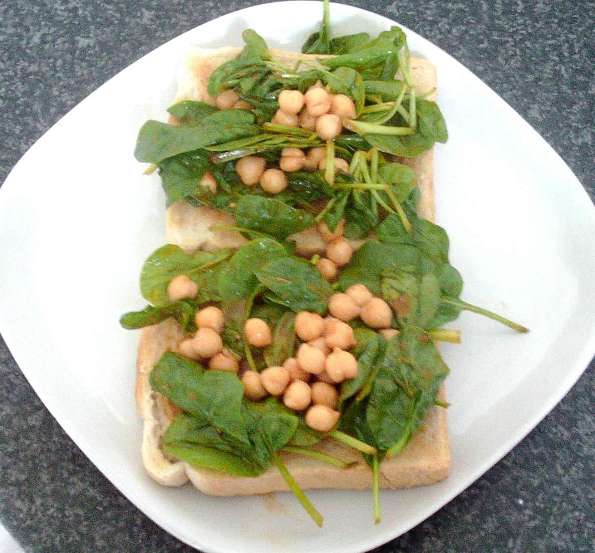 Chickpeas and spinach in tomato sauce are arranged on top of the toast