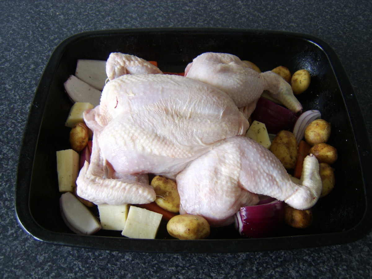The chicken is laid on top of the roughly chopped root vegetables