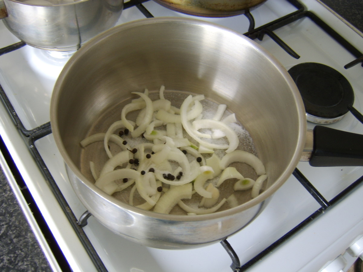 The sliced onion, black peppercorns and salt are added to a large pot.