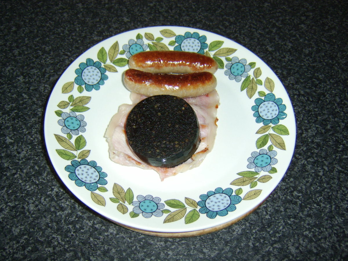 The sausages, bacon and black pudding are transferred to a heated plate and covered with foil to keep warm