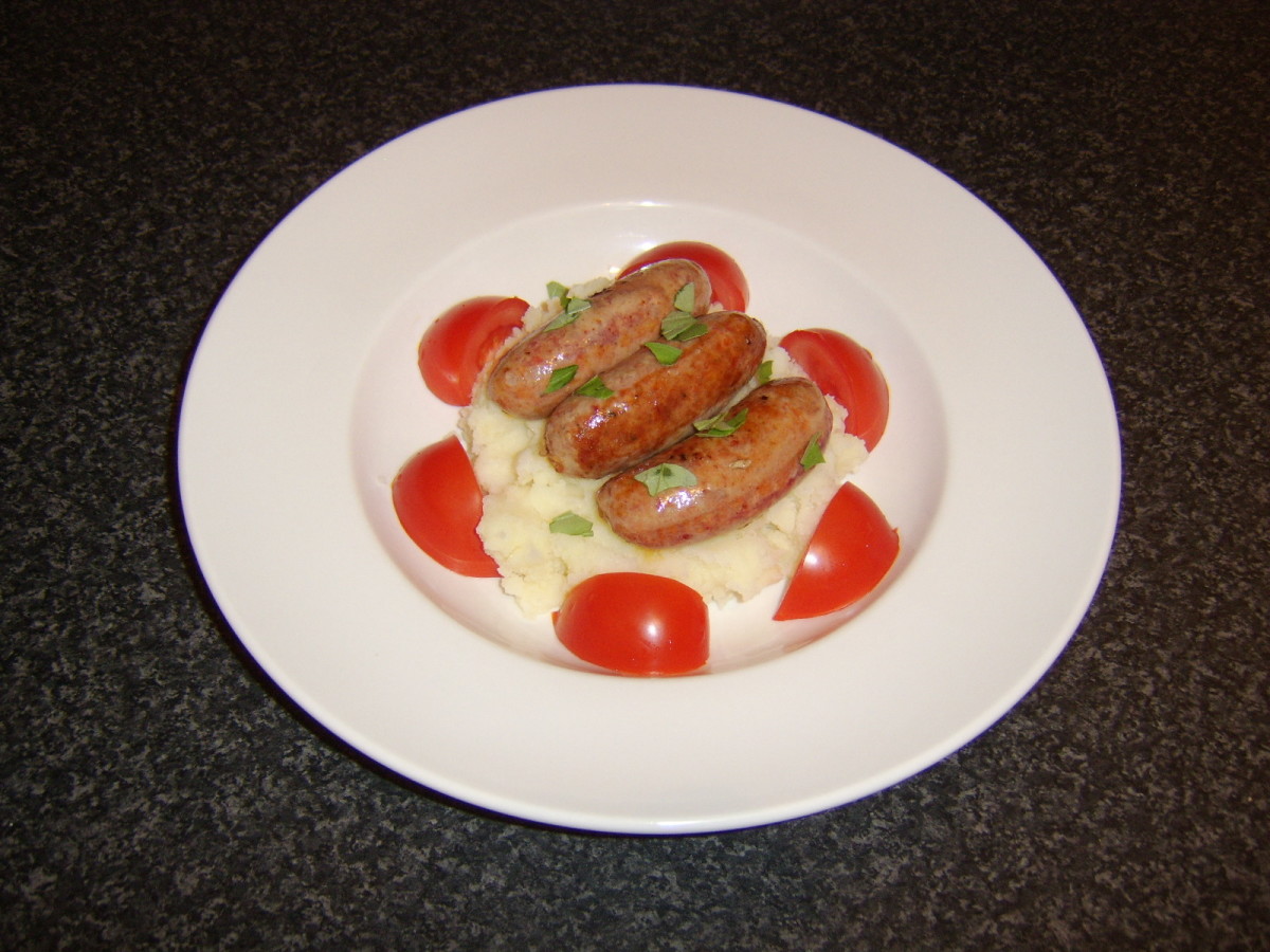 The spicy pork and chorizo sausages are laid on a bed of garlic mash and garnished with torn basil leaves and tomato wedges