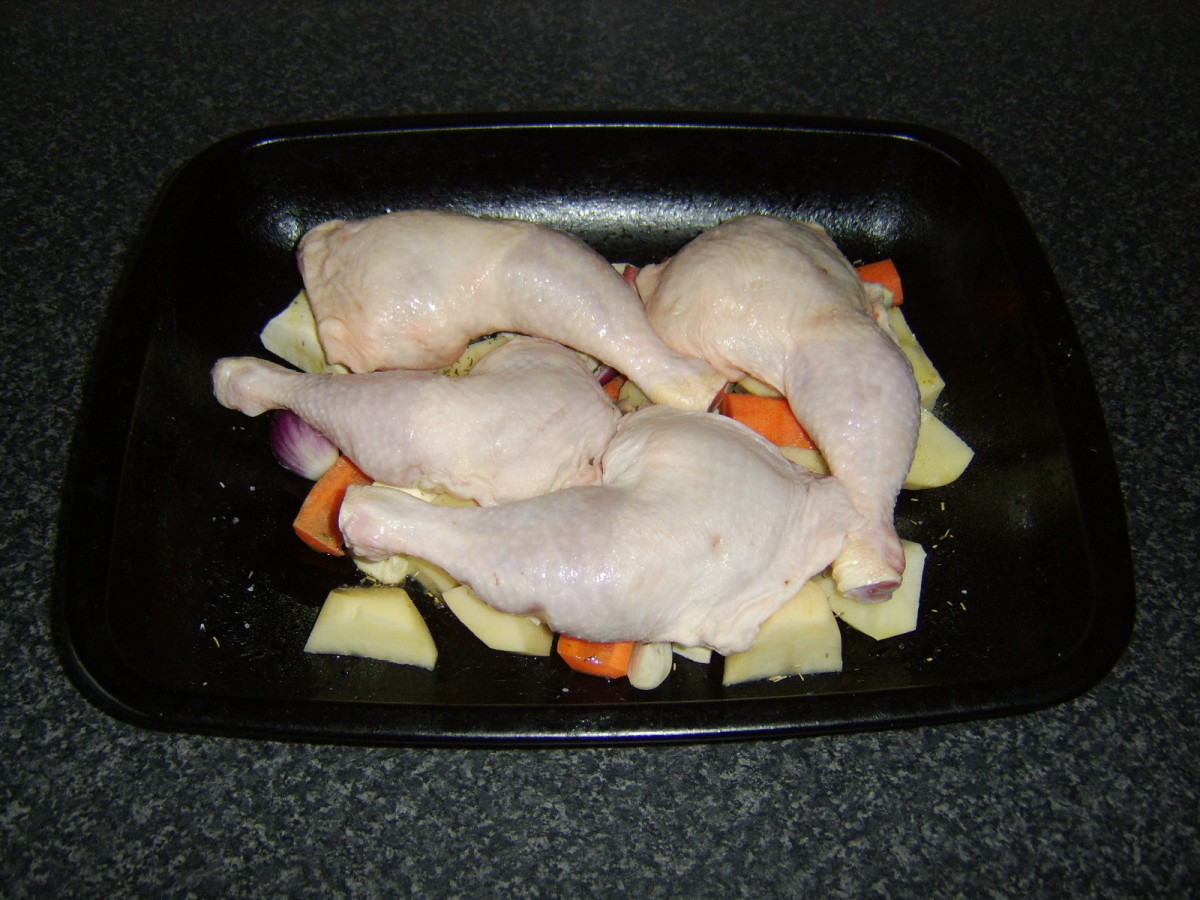 Chicken leg portions are laid on top of the vegetables