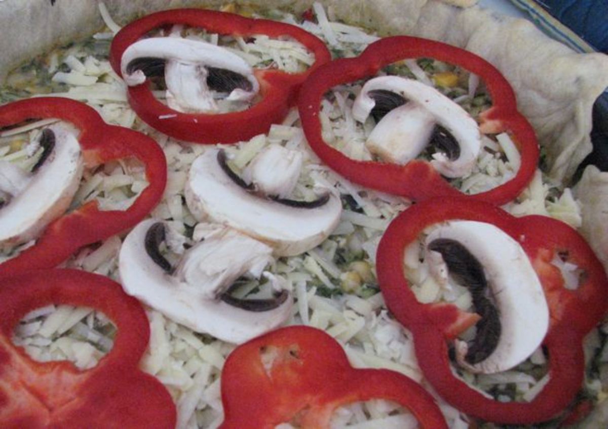 Garnishing the kale vegetable pie with red bell peppers and mushrooms