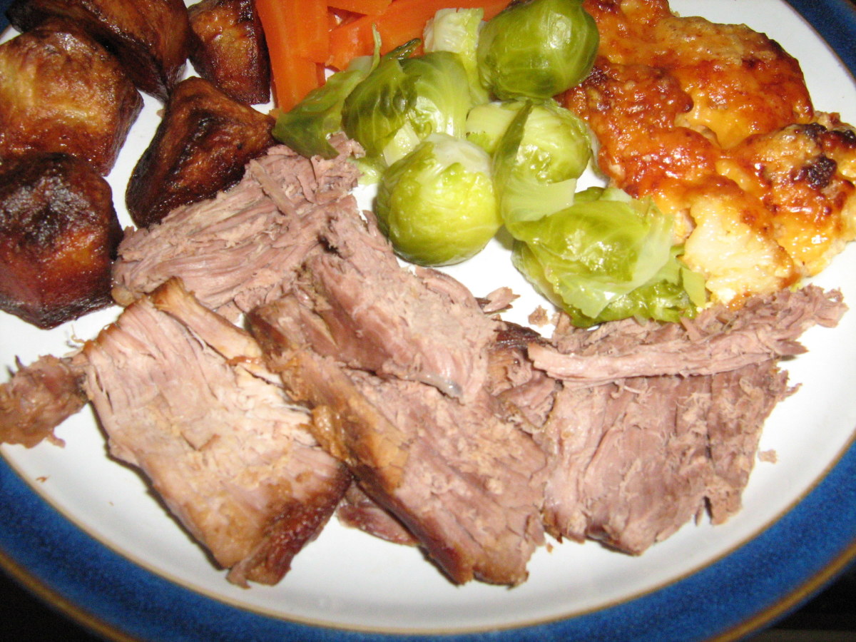 Roast lamb with sprouts, carrots, roast potatoes, and cauliflower cheese