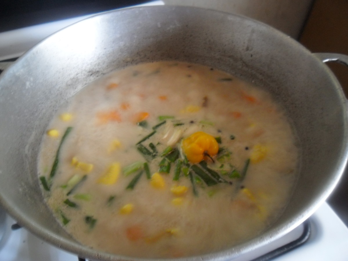 When coconut milk starts to boil, add ackee, scallion, and Scotch bonnet, and cover. 
