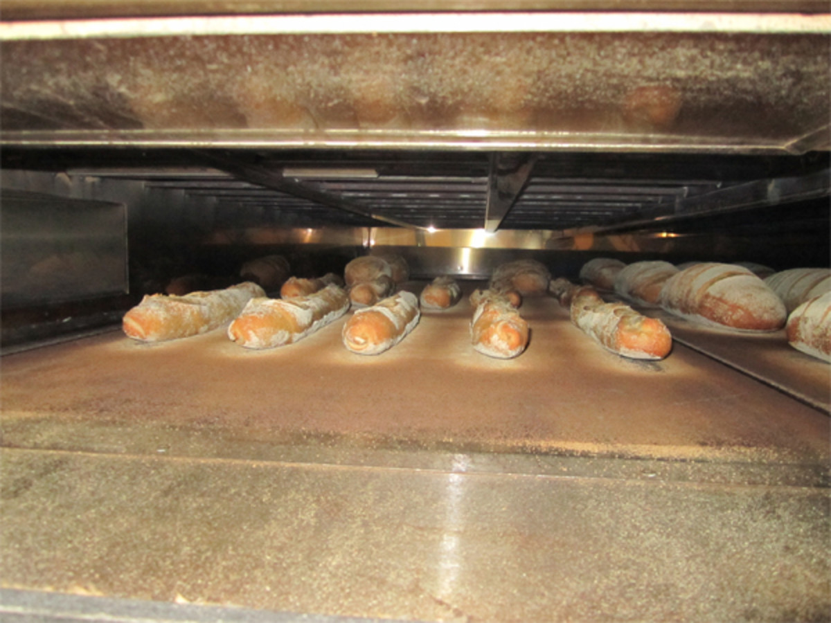 Freshly baked baguettes ready to come out from baker's oven. In these ovens, water is pushed in over hot elements at the rear of the oven. This then drifts inot the oven as steam. 