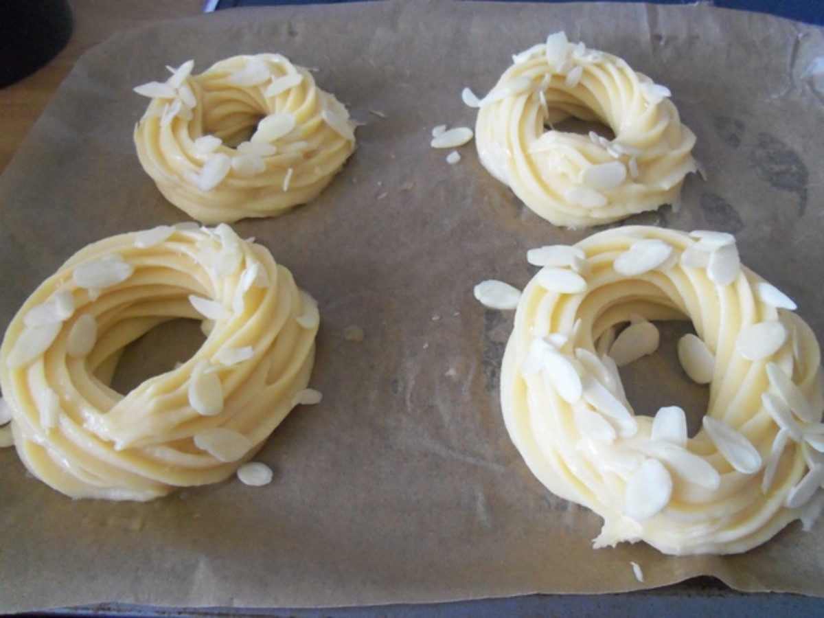 Pipe two layered circles of pastry, brush with egg wash and sprinkle with flaked almonds before baking