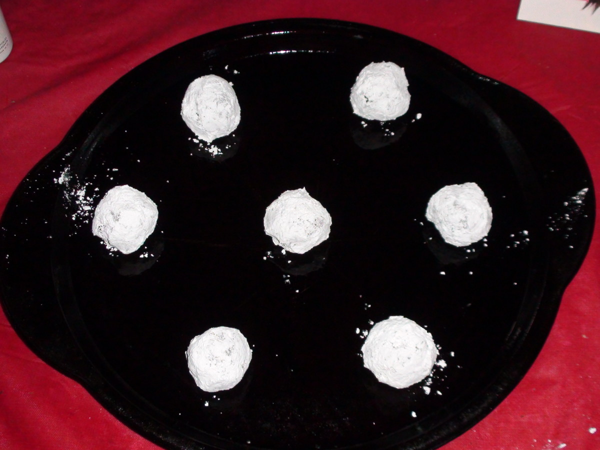 6. Roll the dough into balls, cover in powdered sugar, and place on greased cookie sheet.
