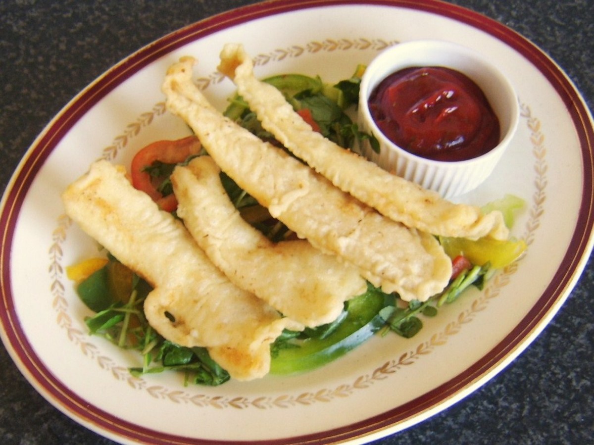 Battered plaice fillets are served on a salad bed and with a spicy tomato based dip