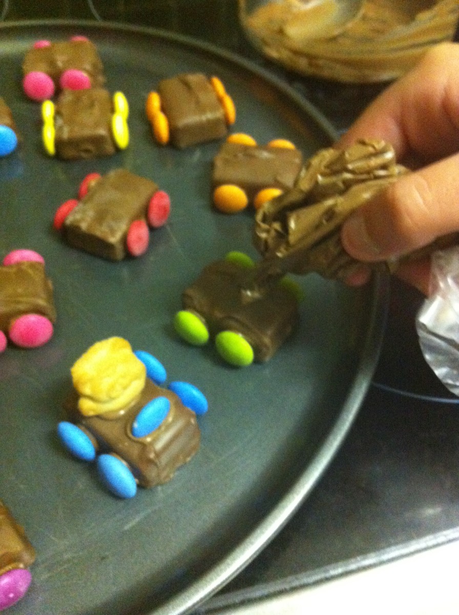 Use the rest of the melted chocolate to add the half Smartie steering wheels and the Tiny Teddy drivers.