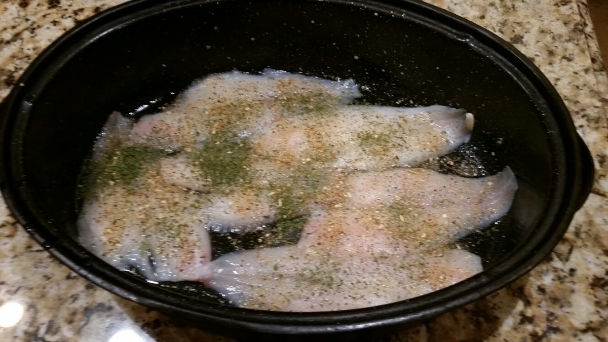 Layer the pieces of fish in the pan. Add salt. Sprinkle the lemon pepper seasoning and parsley on each piece of fish.