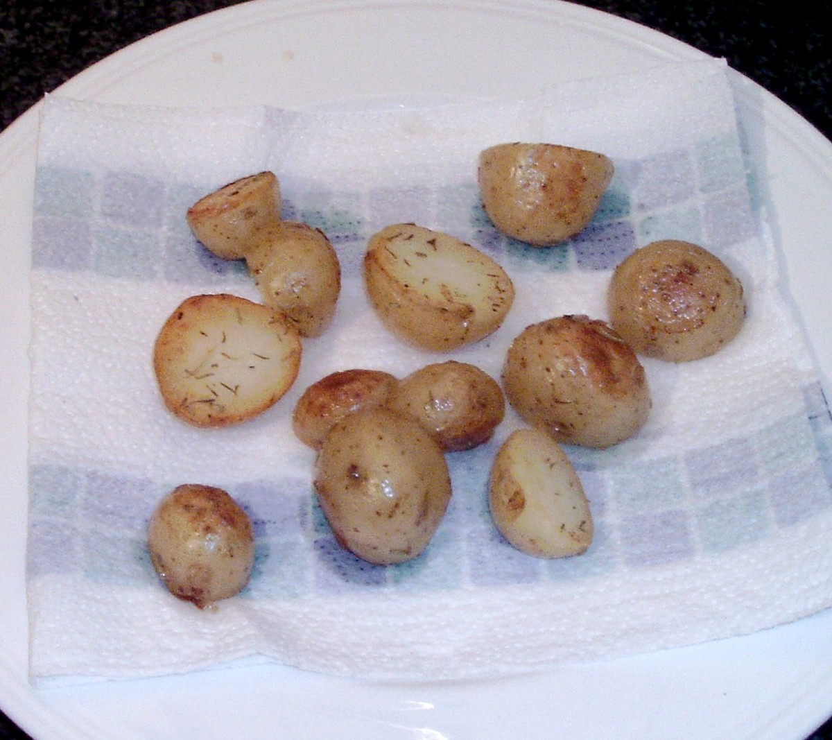 Herb and garlic roasted potatoes are drained on kitchen paper
