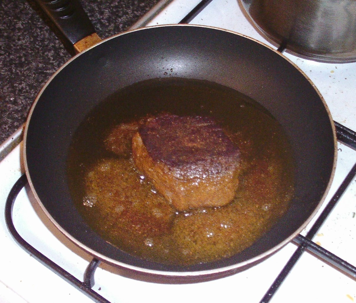 Ostrich steak is turned to fry on second side.
