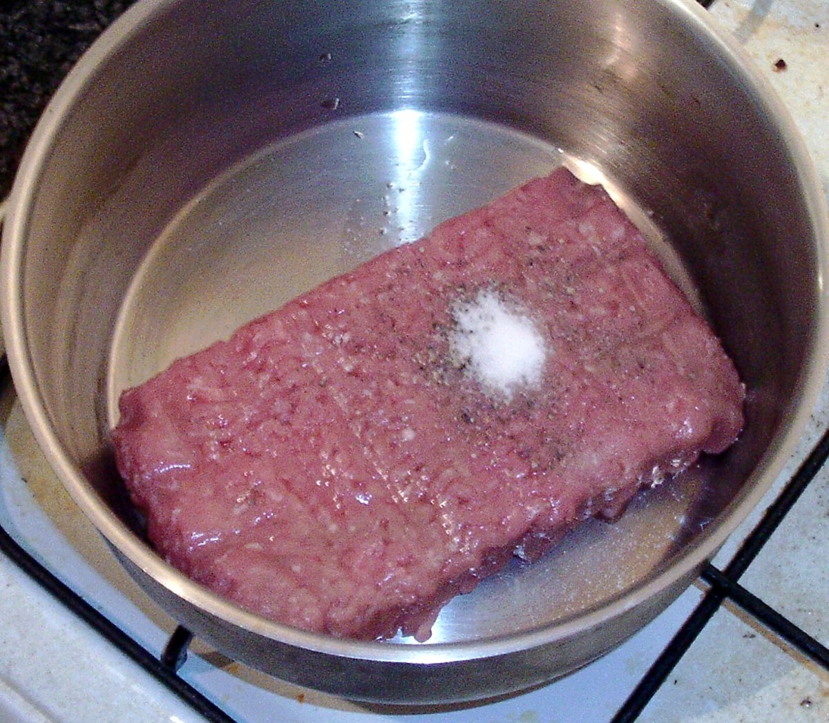 Pork is added to a saucepan and seasoned