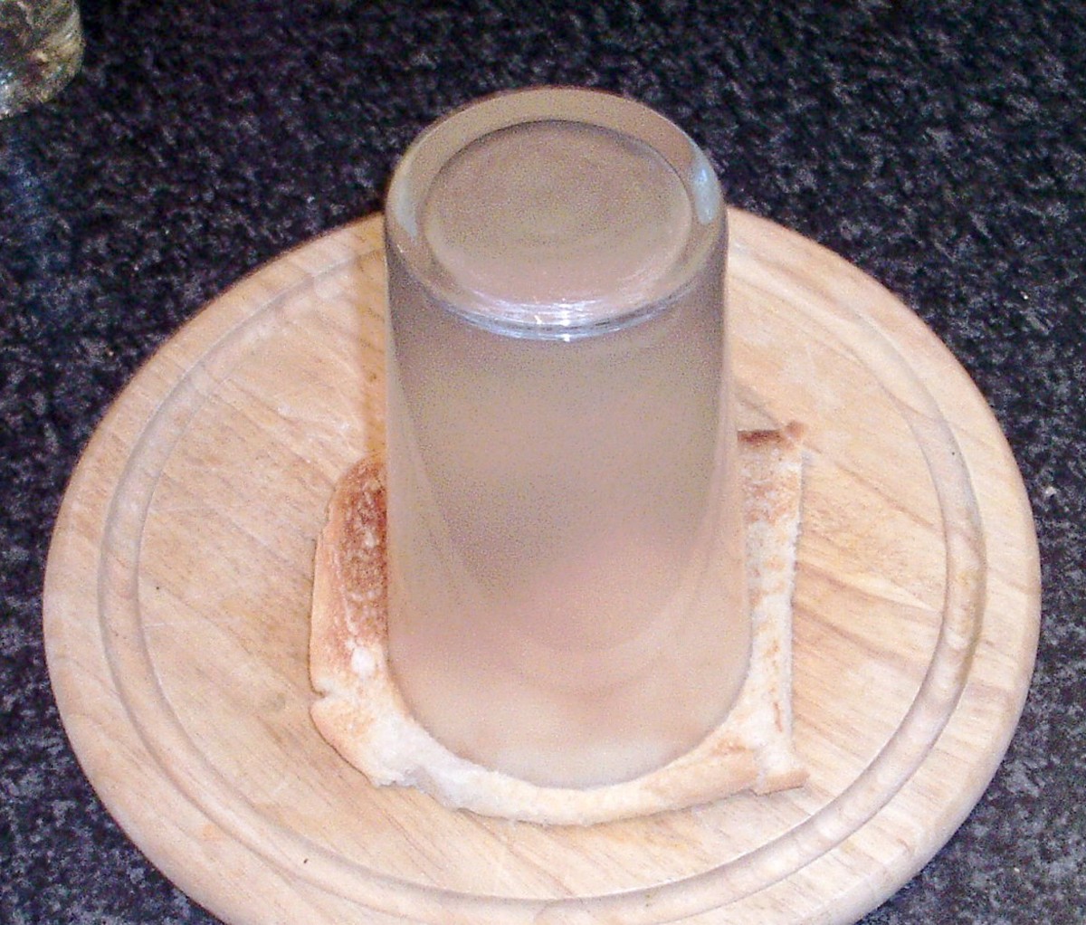 Circle is cut from slice of toast with a large drinking glass