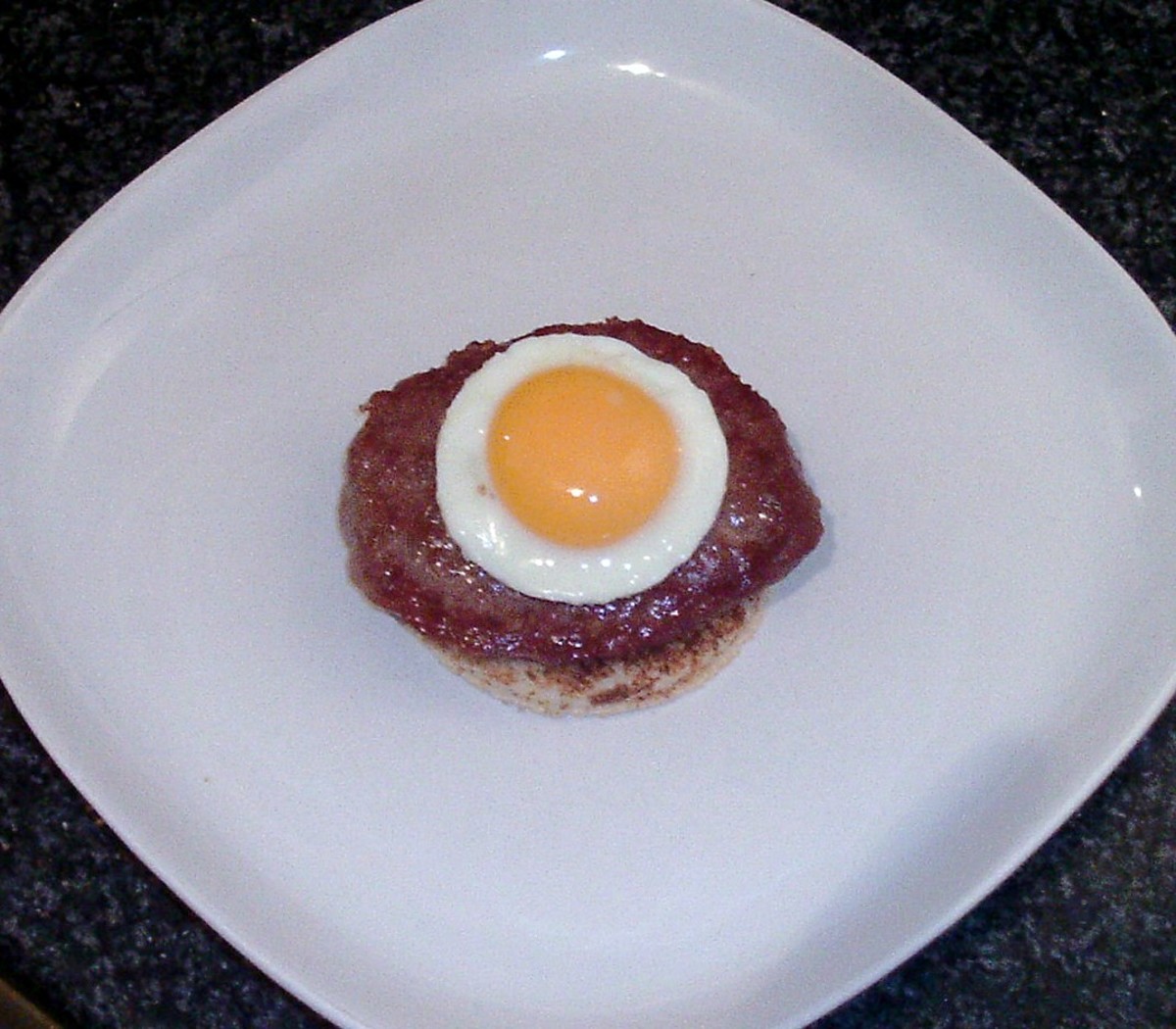 Fried egg circle is laid on top of burger.