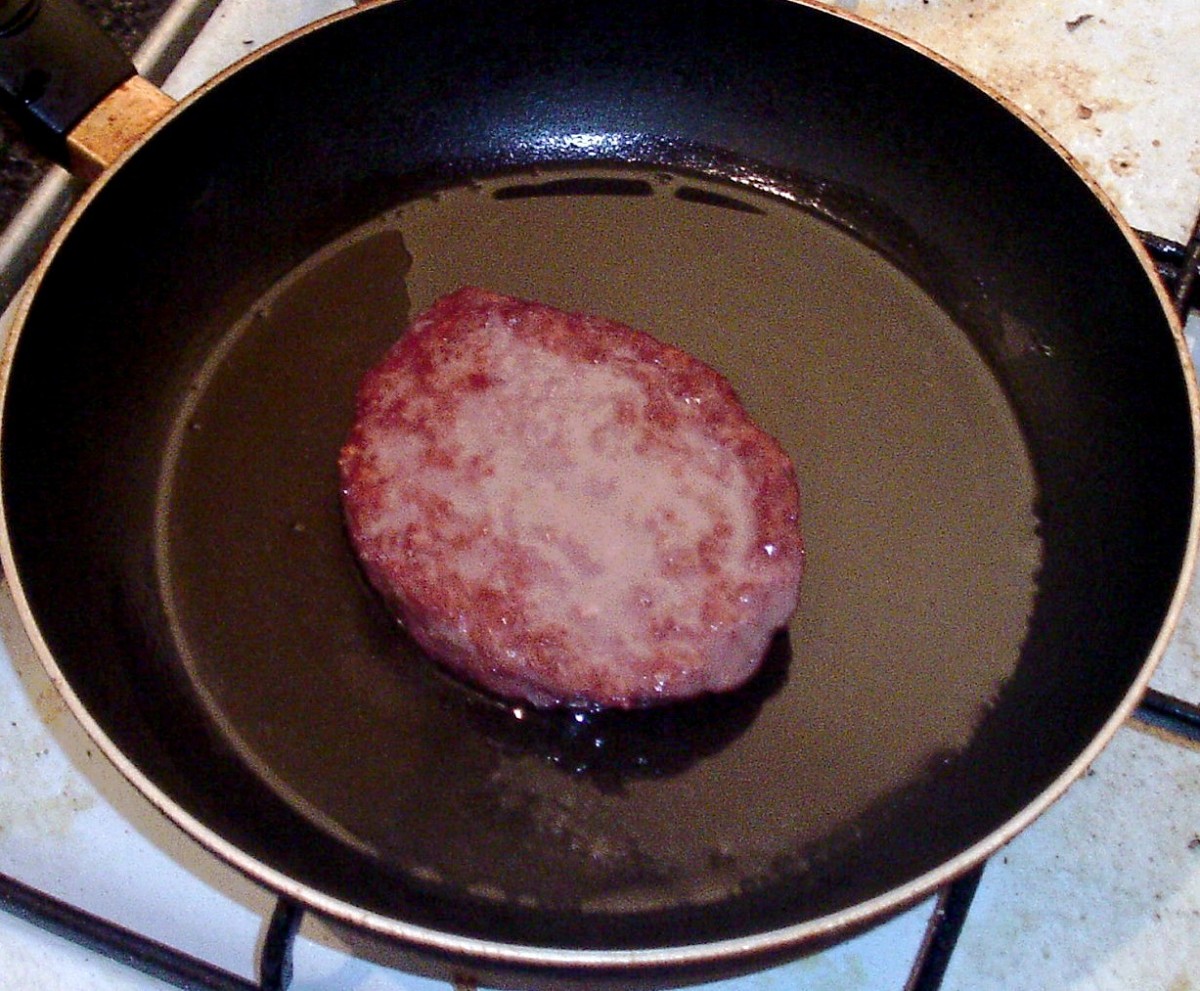 Belgian Blue beef burger is turned to fry on second side.