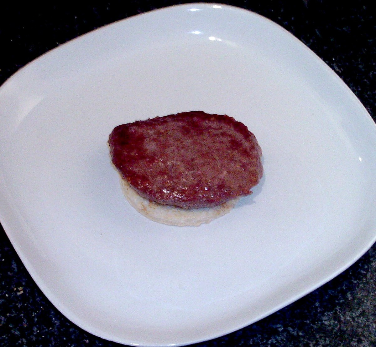 Rested Belgian Blue beef burger is laid on top of toast circle.