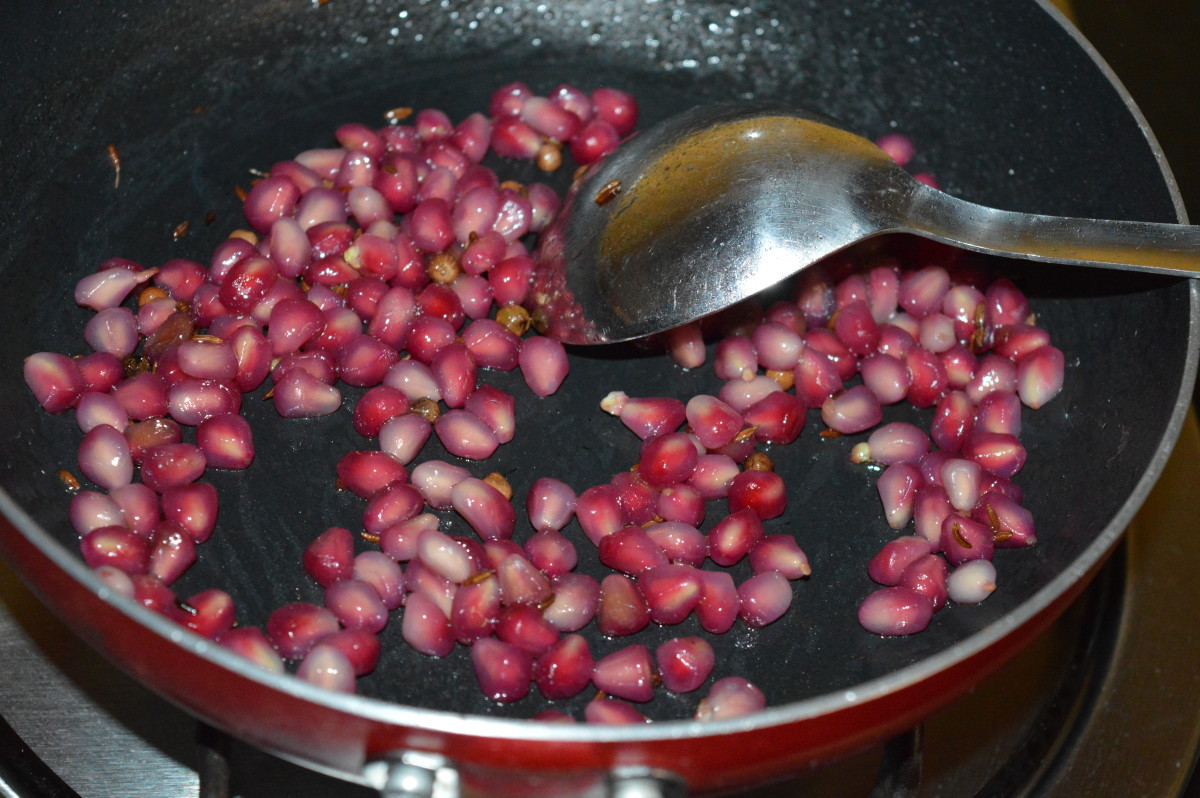 By now, pomegranate seeds should become pale and soft. Add grated coconut. Set aside to cool.