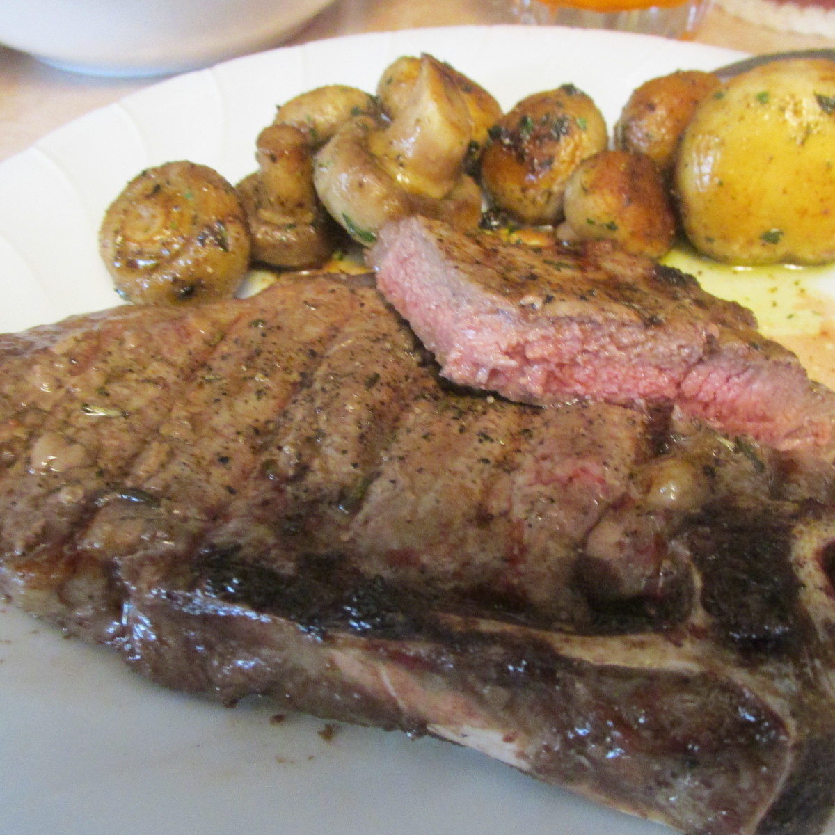 My steak, cooked medium-rare, with mushrooms in the background.
