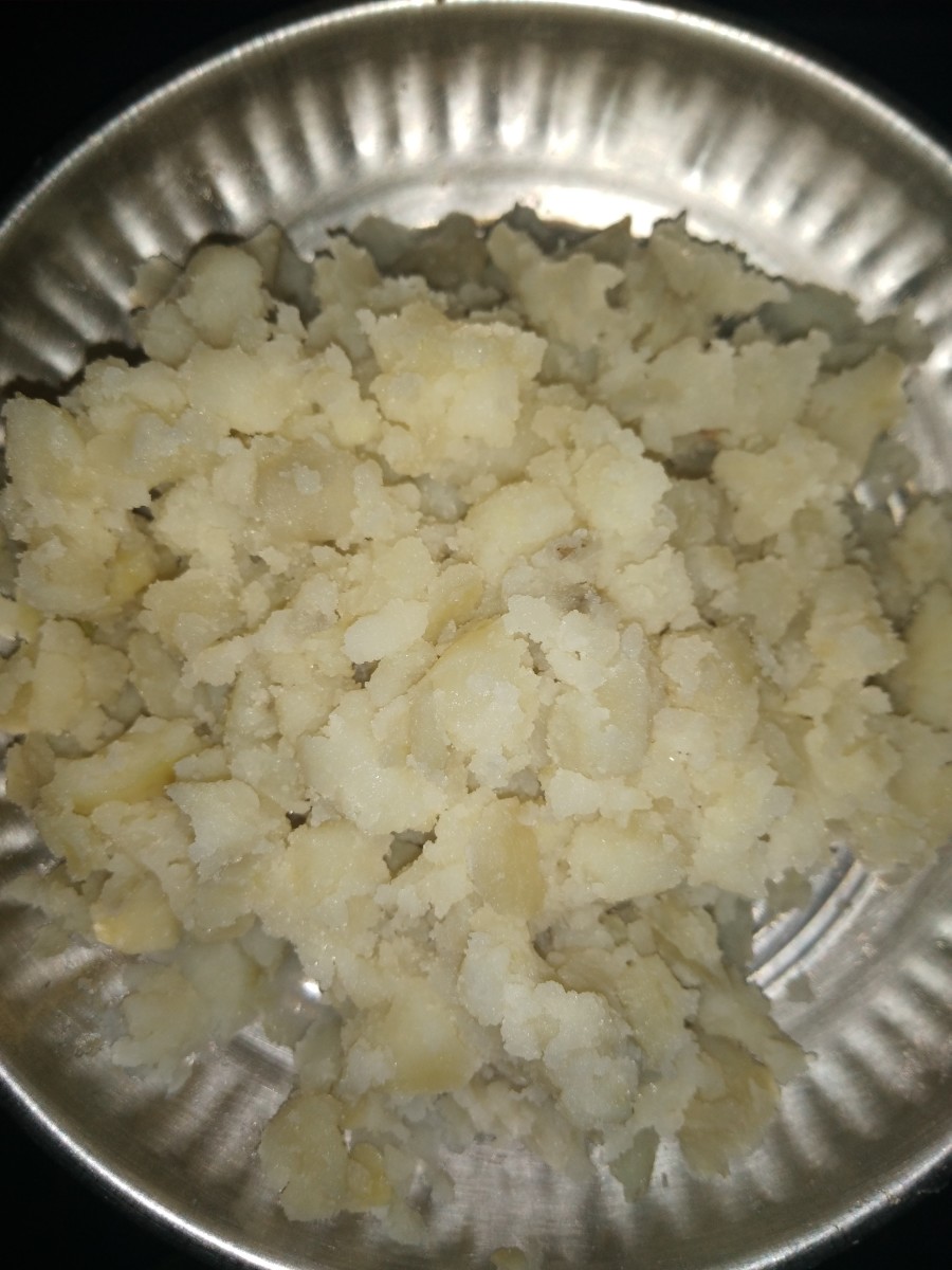 Cook potatoes in pressure cooker. Then, peel skin and mash.