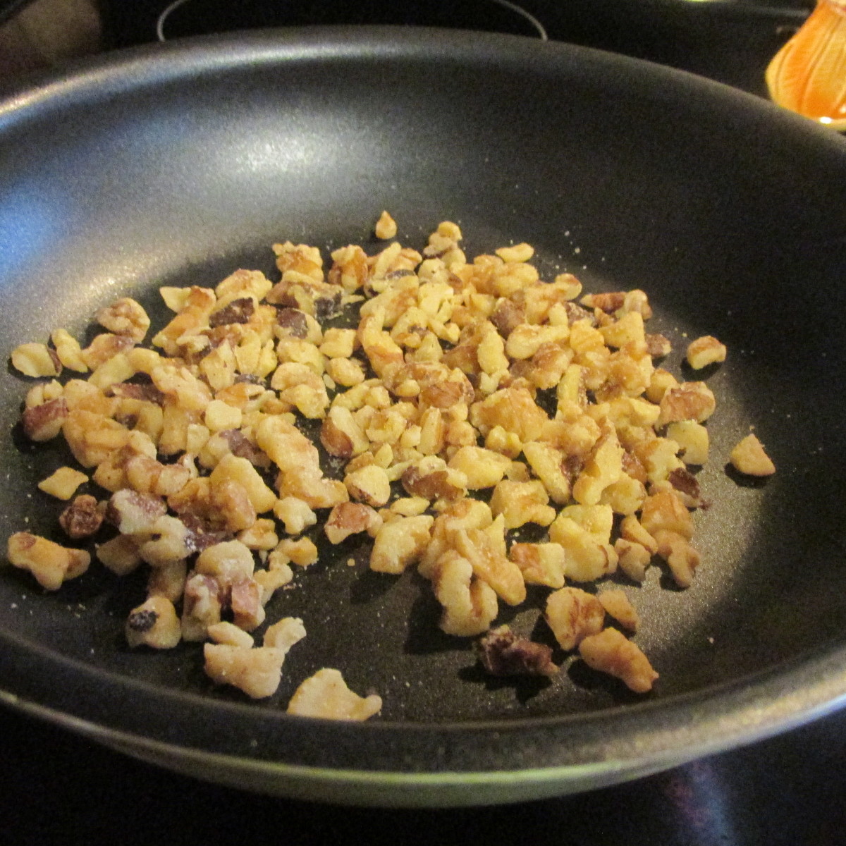 Walnuts toasting in a small pan.