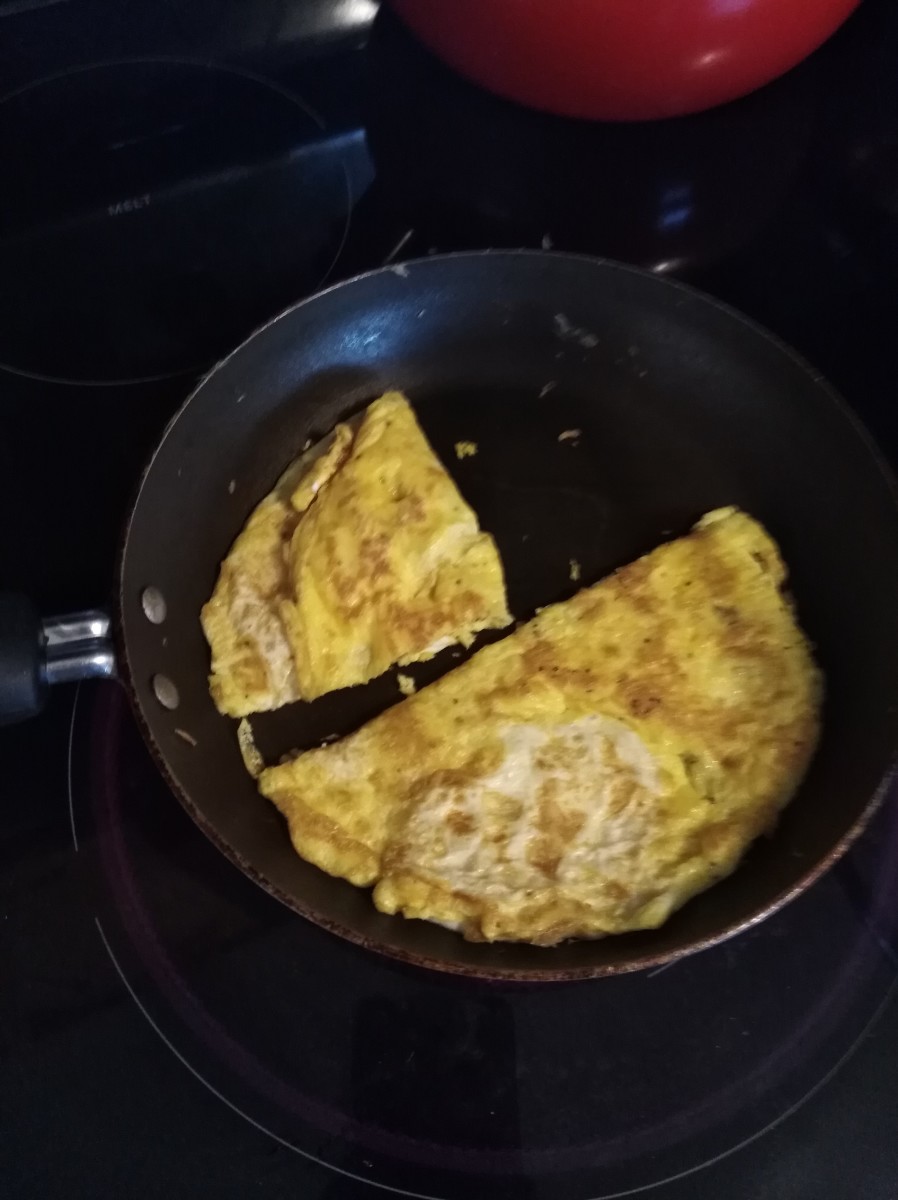 After the egg is cooked, take the spatula and cut the egg in half in the pan.