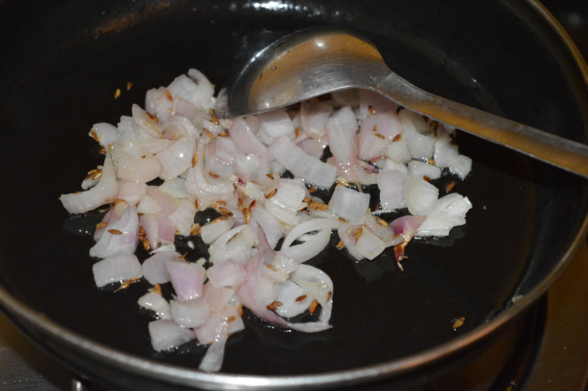 Step two: Saute cumin seeds in oil until they crackle. Add chopped onions and continue sauteing until they become pinkish.