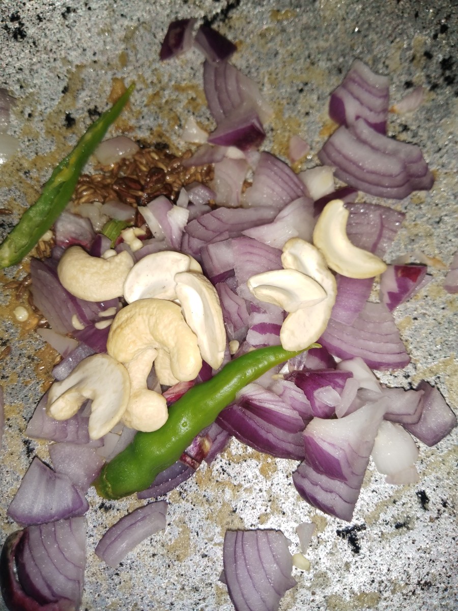 Add chopped onion, cashew nuts, and green chili. Fry.