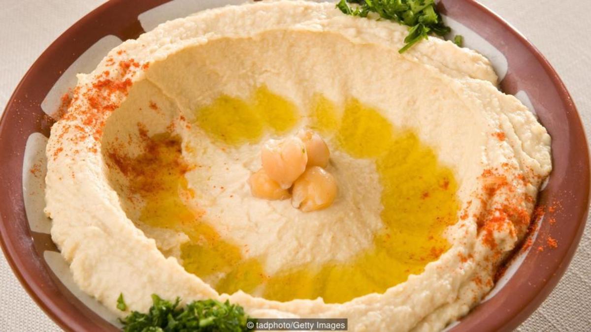 Hummus is traditionally served in a red clay bowl with a raised edge.