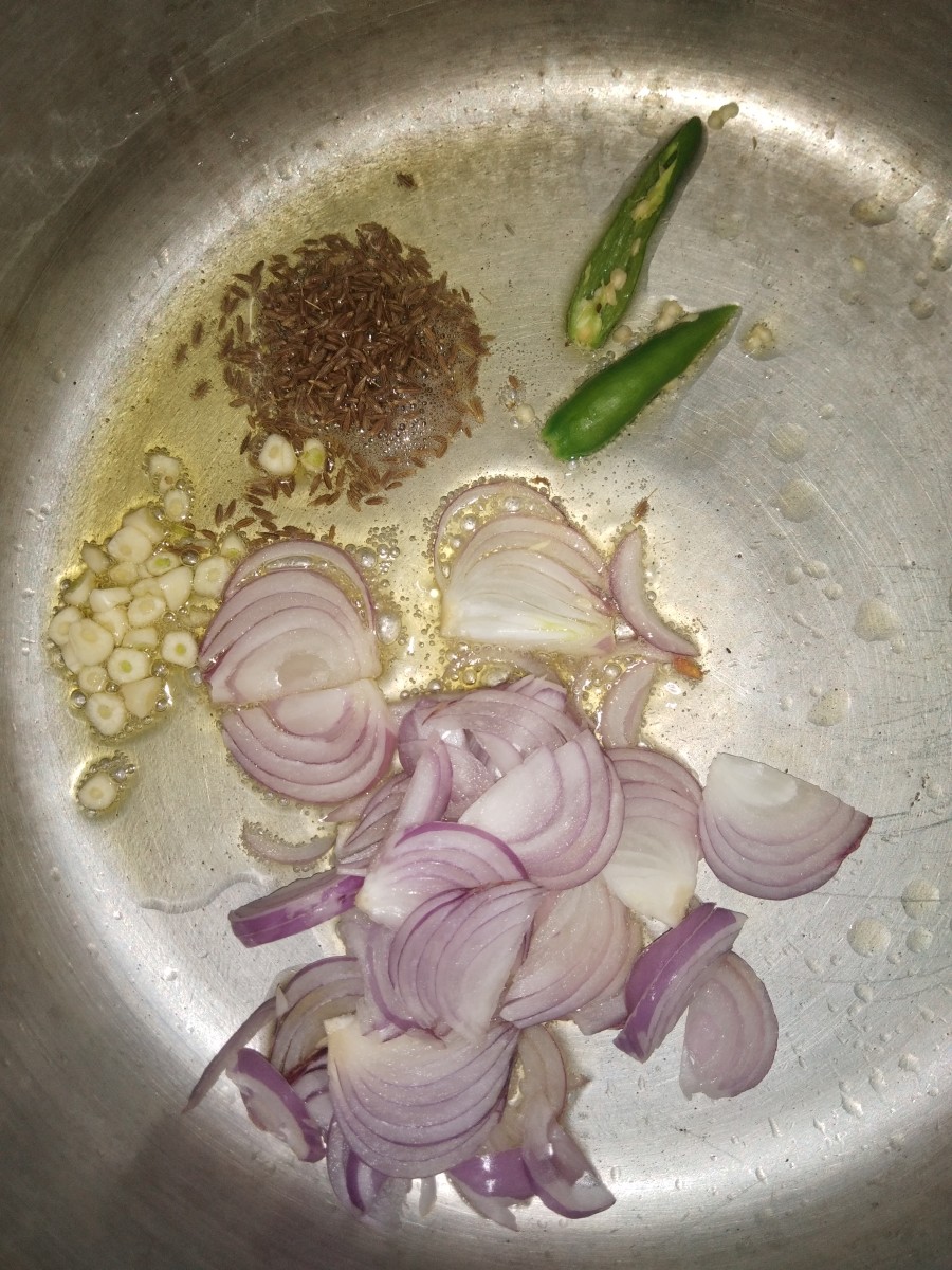 In a cooker, heat oil or ghee. Add cumin seeds and let it splutter. Add sliced onion, garlic, and green chilies.